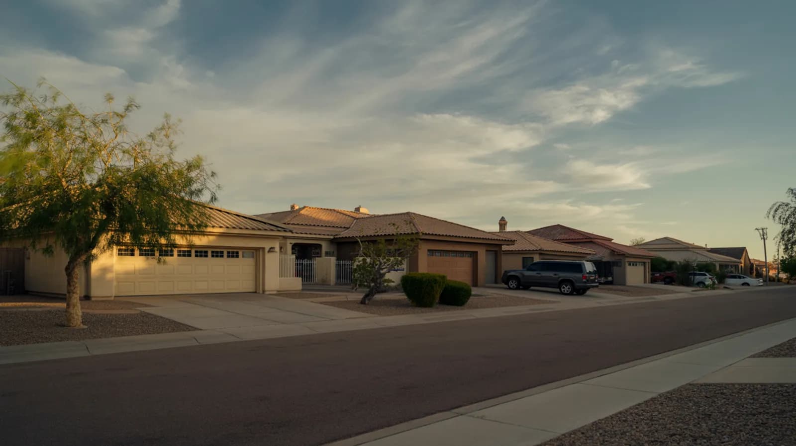 Quiet Arizona suburban residential street at warm evening light with tile-roofed homes